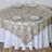 Round table covered with elegant gold floral lace tablecloth and white plates.