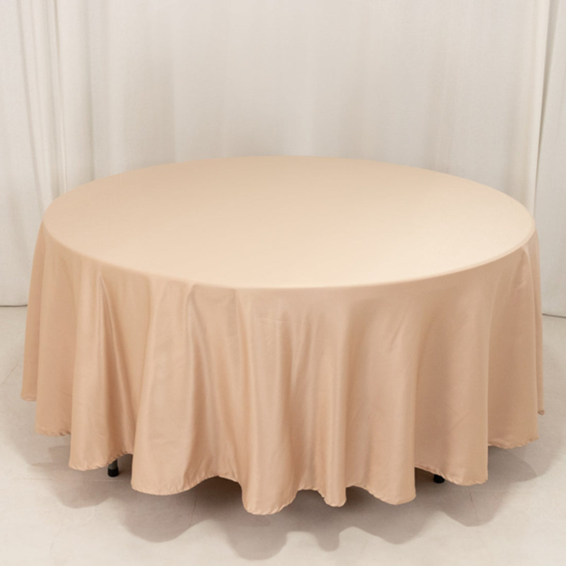 Round beige tablecloth draped over a circular table.