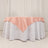 Round table with a white tablecloth and a pink satin overlay