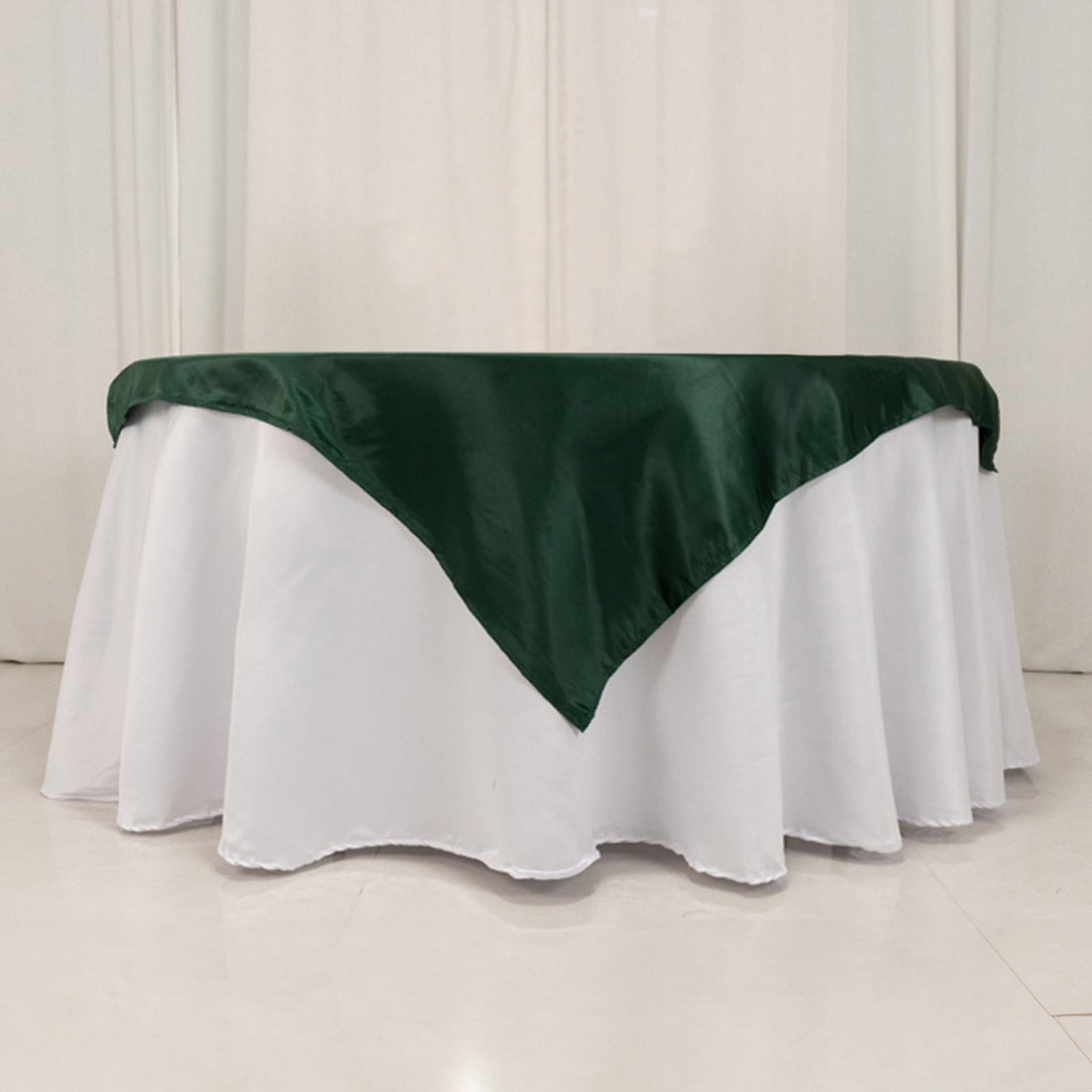 Green satin tablecloth draped elegantly over a white table.