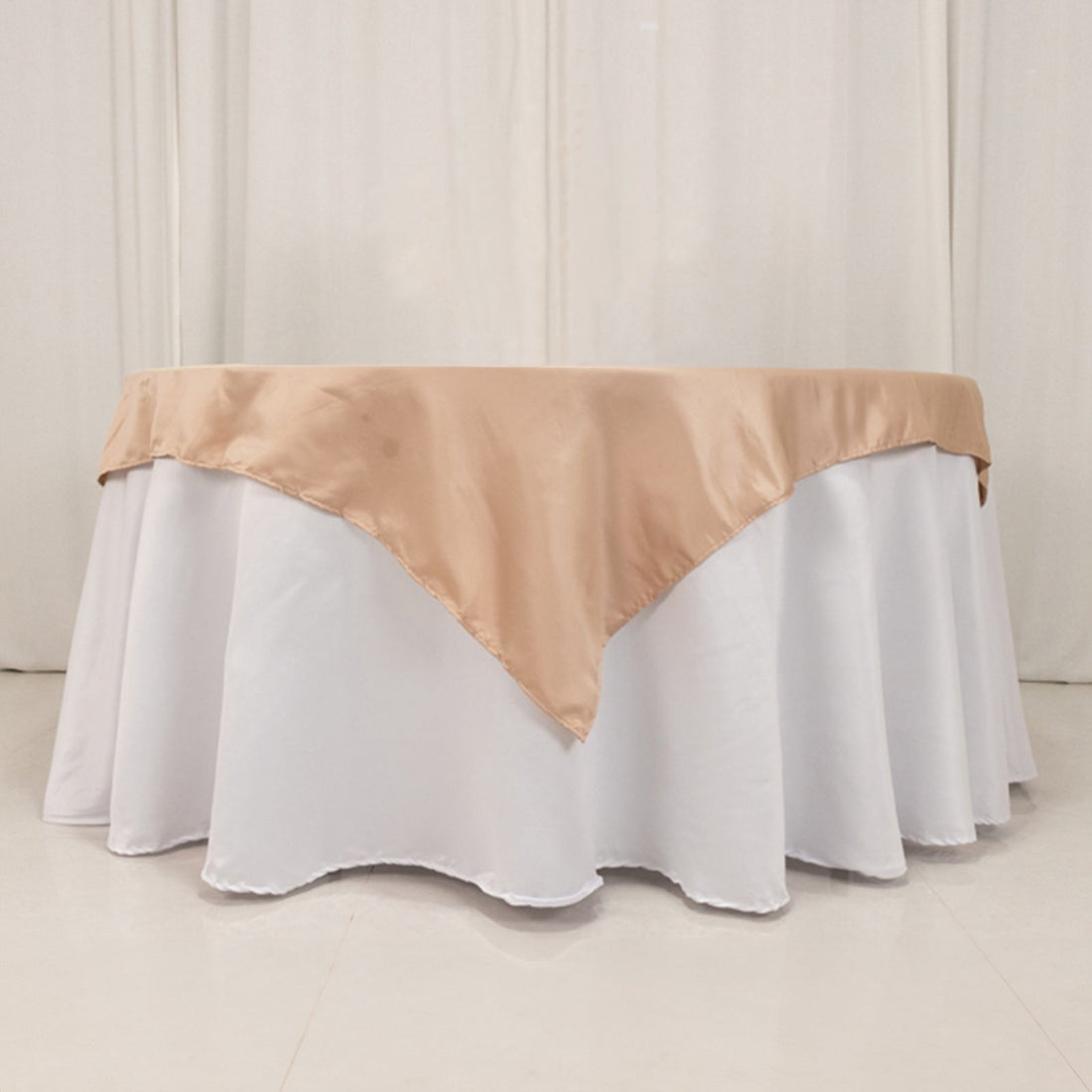 Table with white skirt and beige satin overlay, suitable for events.