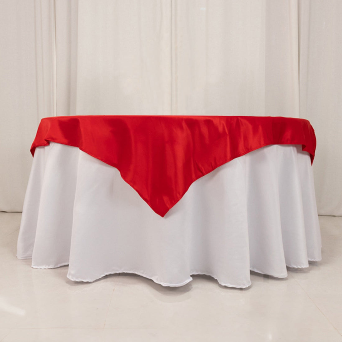 Red satin tablecloth draped elegantly over a white table.