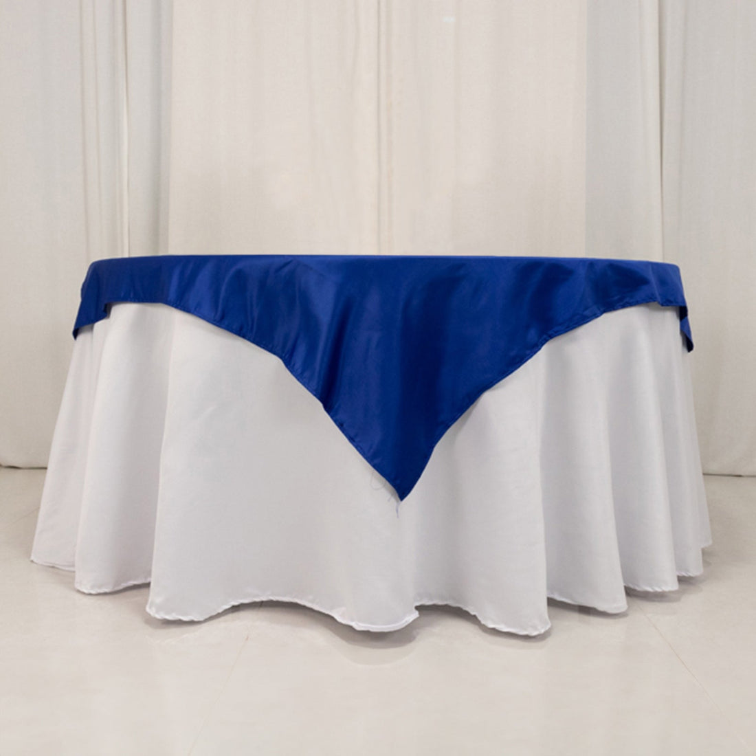 Blue satin tablecloth on a round white table.