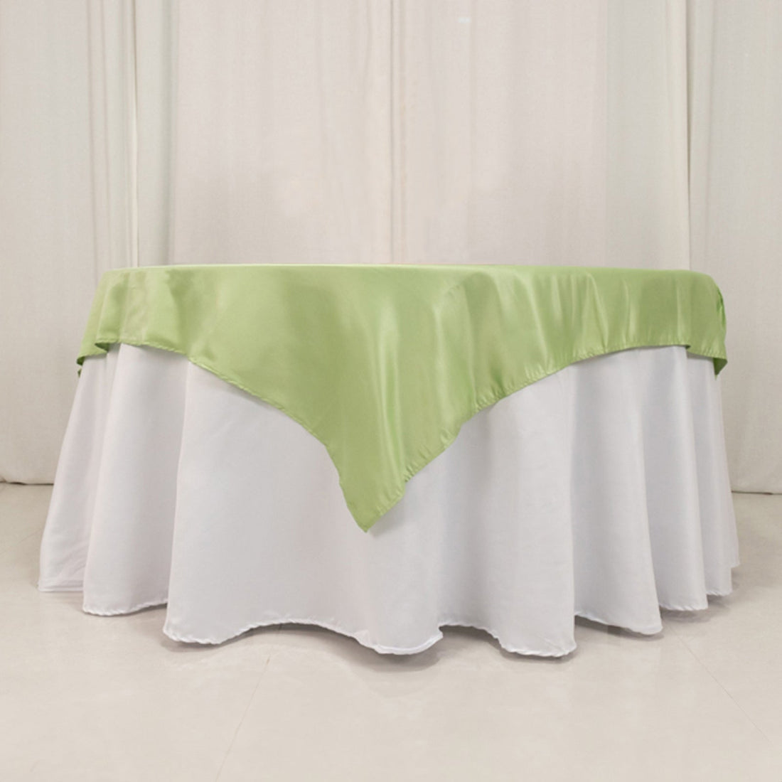 Green satin tablecloth draped over a white table.