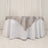 Elegant round table with white tablecloth and silver satin overlay