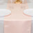 Peach satin table runner on a white table with elegant dinnerware.