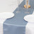 Blue satin table runner on a white table with plates and glasses.