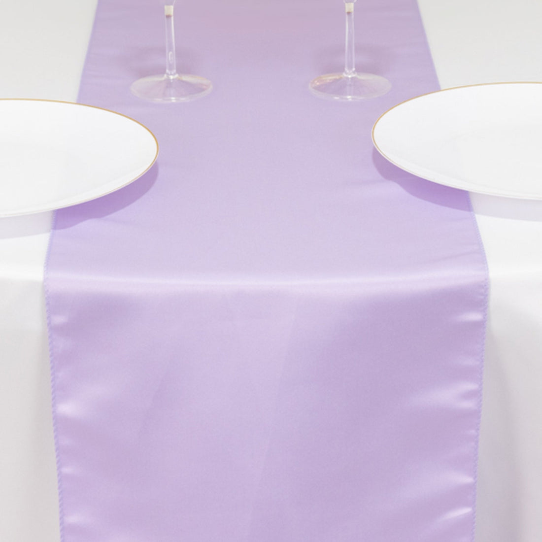Lavender table runner on a white table with plates and glasses