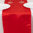 Red satin table runner on a white table setting with plates and glasses.