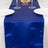 Navy blue satin table runner on a white table with plates and glasses.