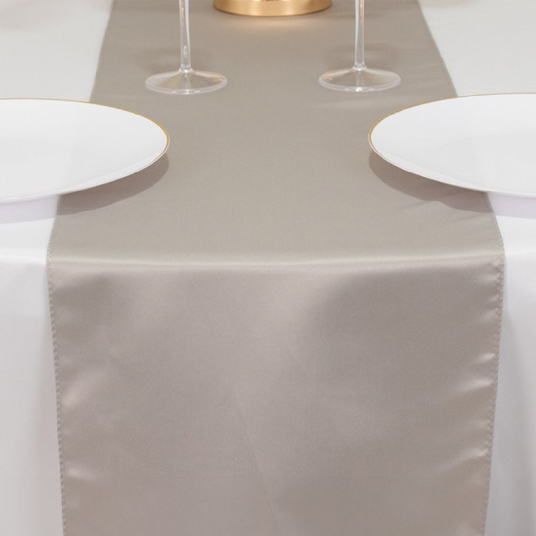 Elegant beige table runner on a dining table set with plates and glasses.