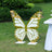 Gold and white butterfly decoration in a garden setting.