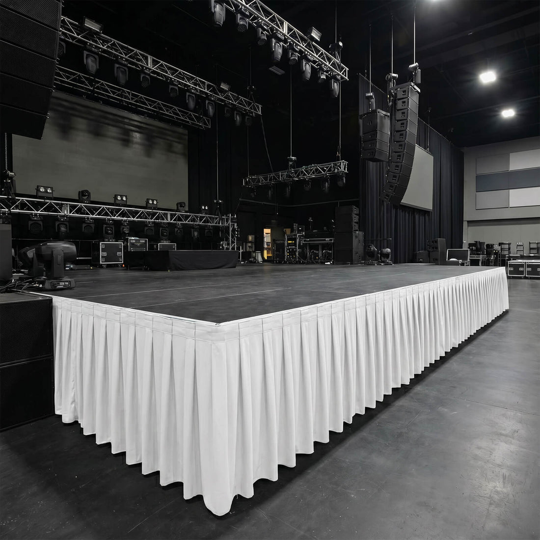 Large concert stage setup with lighting trusses and hanging speakers in a venue