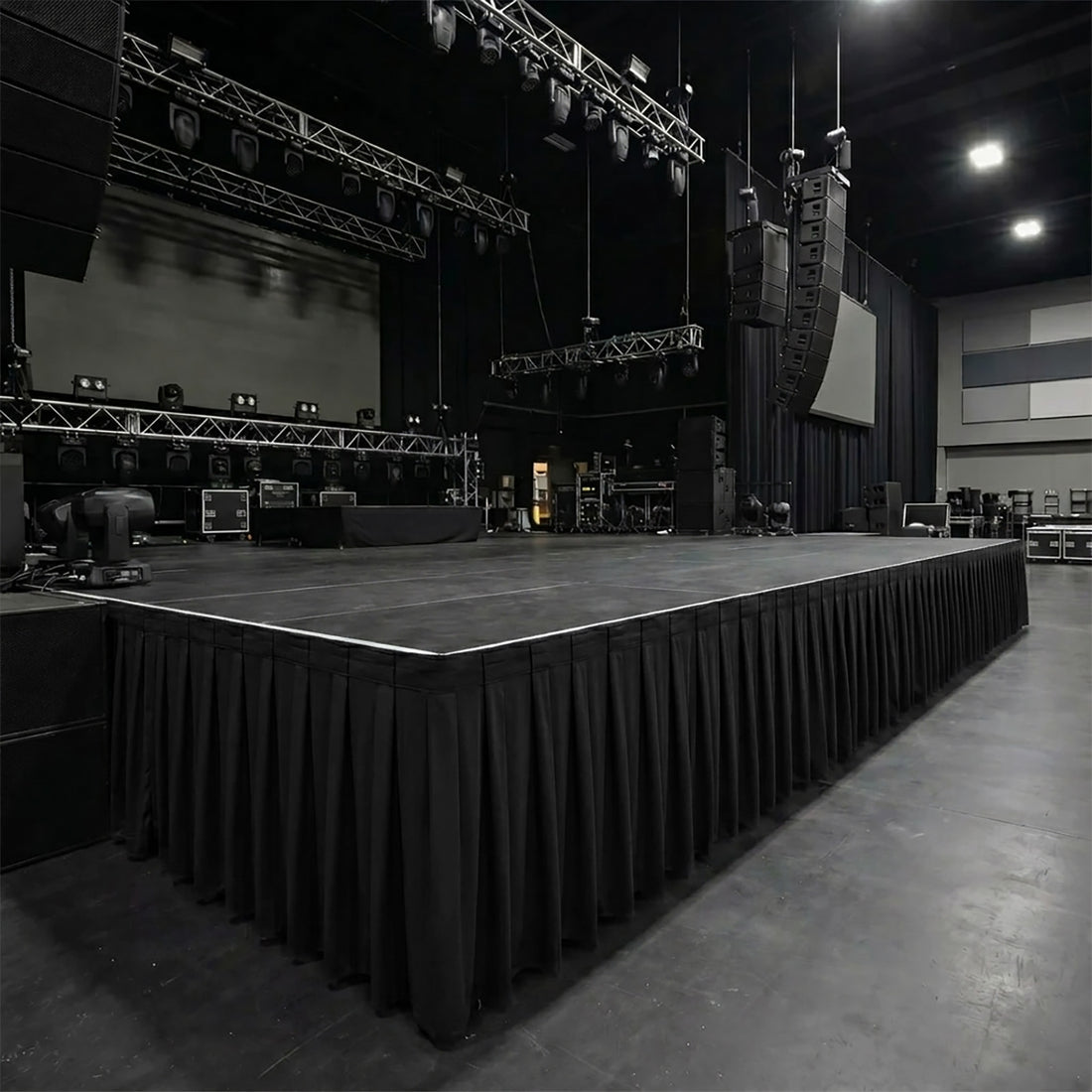 Large empty concert stage with hanging speakers and lighting rig in dark venue