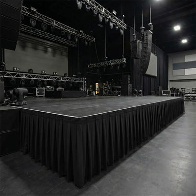 Large empty concert stage with hanging speakers and lighting rig in dark venue