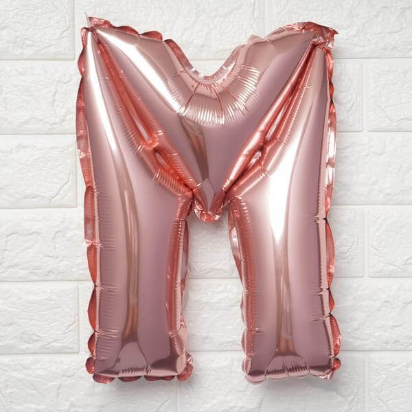 Rose gold letter M balloon on a white backdrop