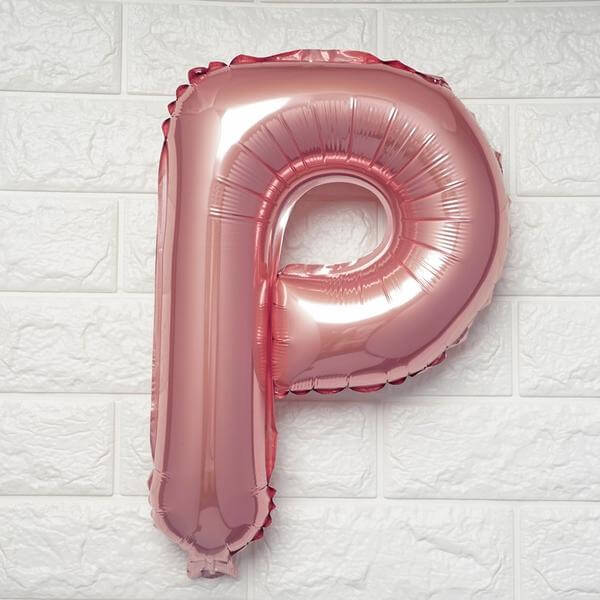 Rose gold letter P balloon on a textured white wall.