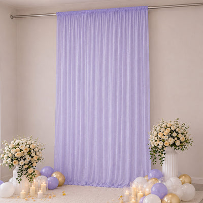 Lavender backdrop with floral arrangements, balloons, and candles for elegant event decor