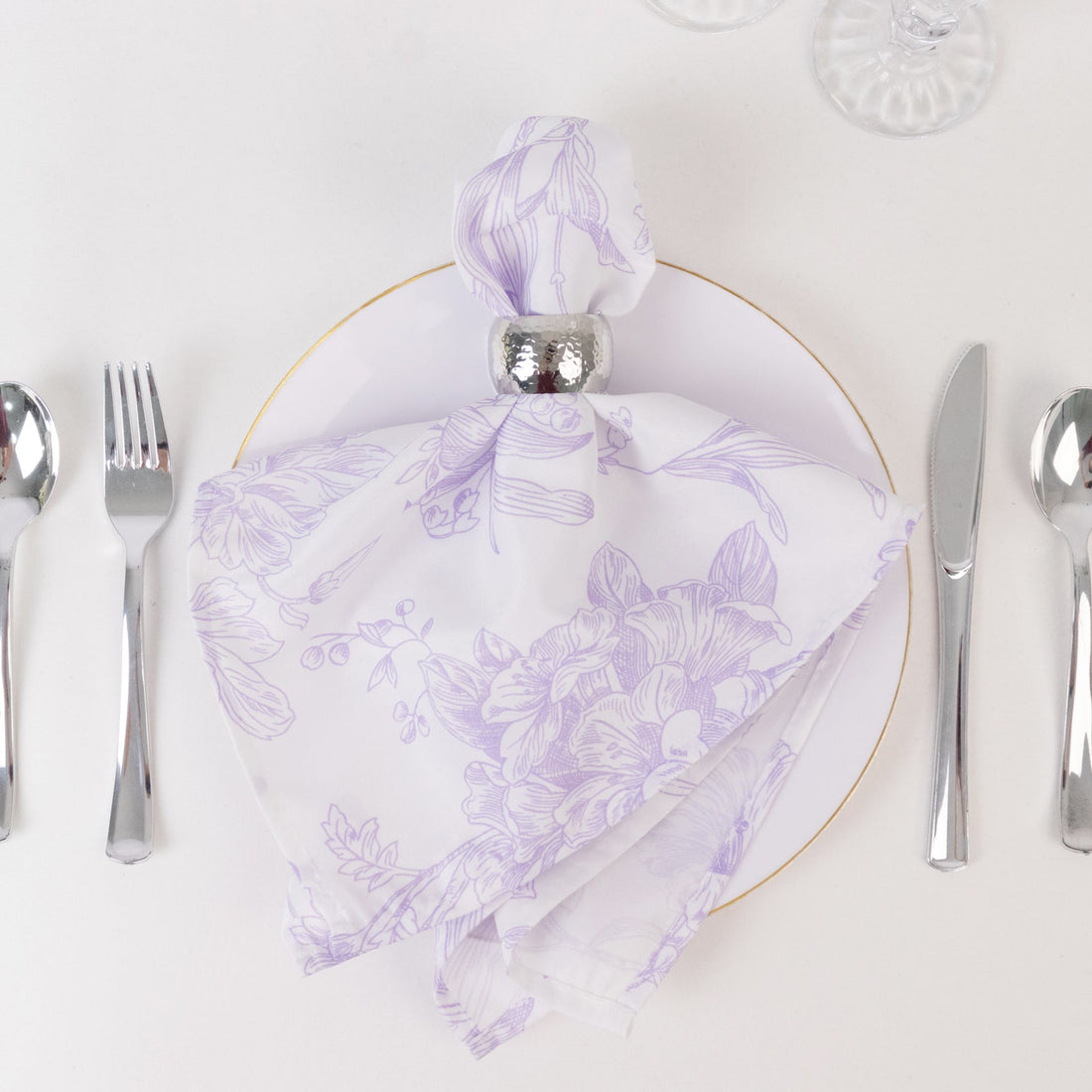 Elegant lavender floral napkin on a white plate with silver cutlery.