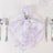 Elegant lavender floral napkin on a white plate with silver cutlery.