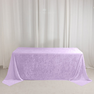 Lavender velvet tablecloth draped over a rectangular table against white curtains