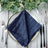 Navy blue pleated napkin on a silver charger plate with cutlery and greenery #whtbkgd