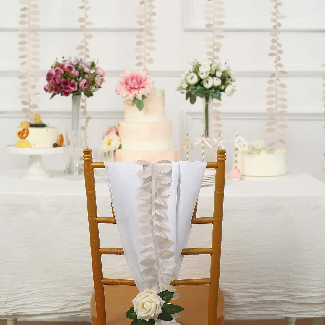 Elegant wedding decor featuring floral arrangements and cake on a decorated table.
