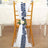 Navy leaf chair sash with white rose on a wooden chair in a decorated event space.