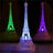Colorful illuminated Eiffel Tower replicas in green, purple, and blue light.
