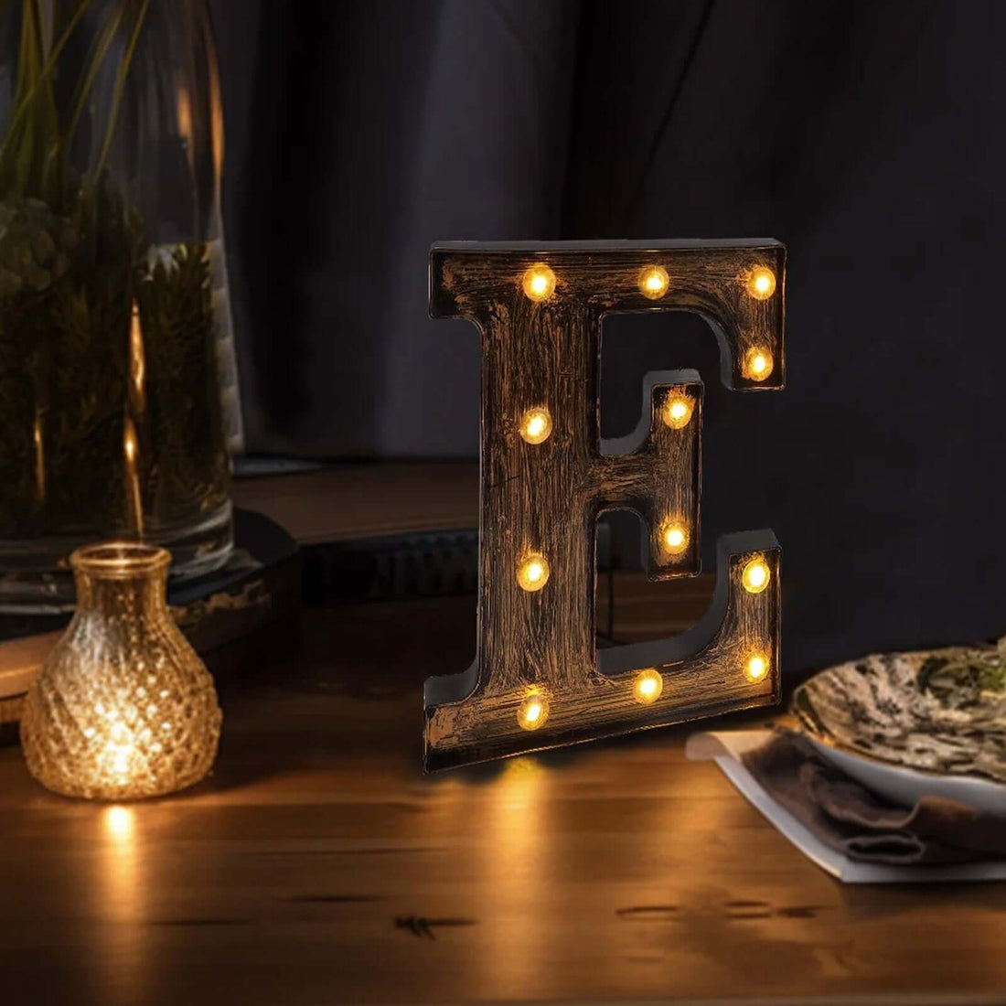 Illuminated marquee letter "E" in rustic style on a wooden table.