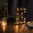 Illuminated marquee letter "E" in rustic style on a wooden table.