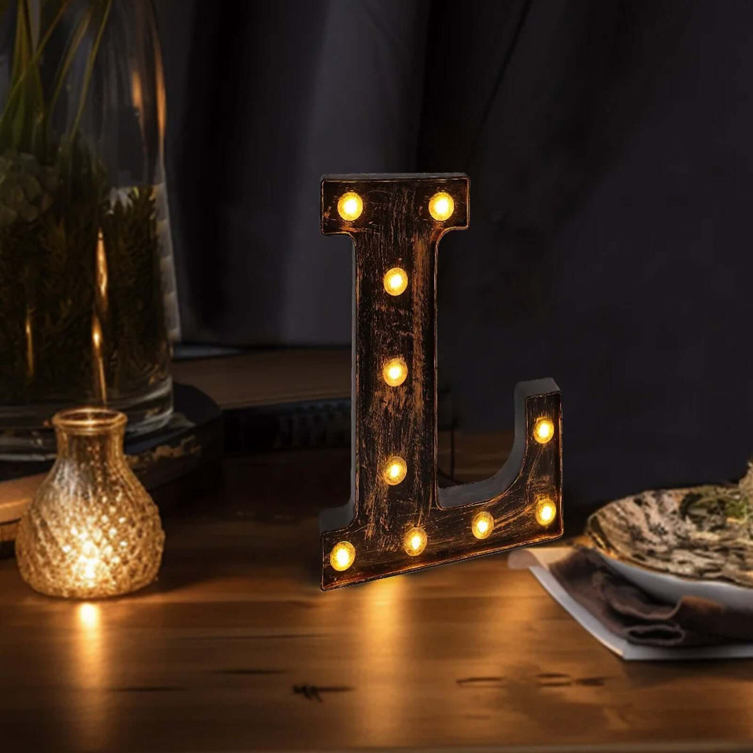 Illuminated vintage letter "L" marquee sign on a wooden table.
