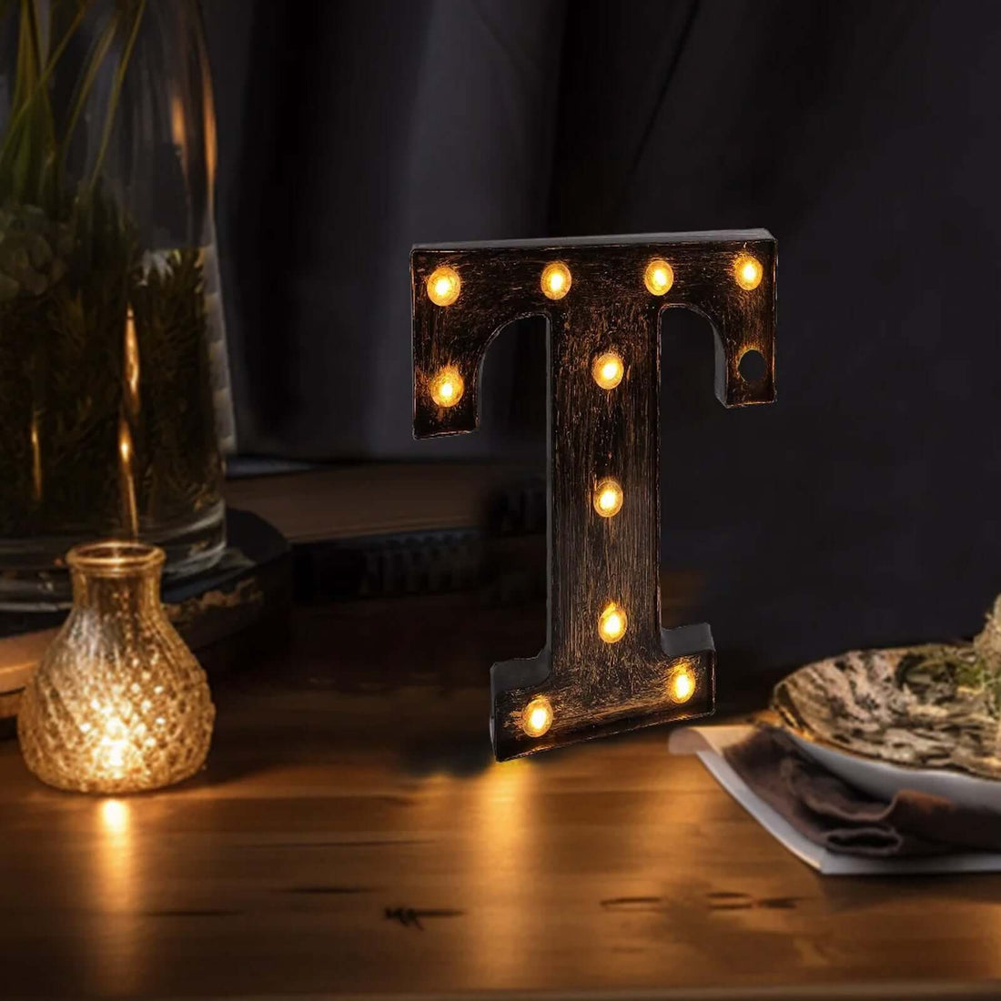 Illuminated vintage-style letter "T" with lights on a wooden table.