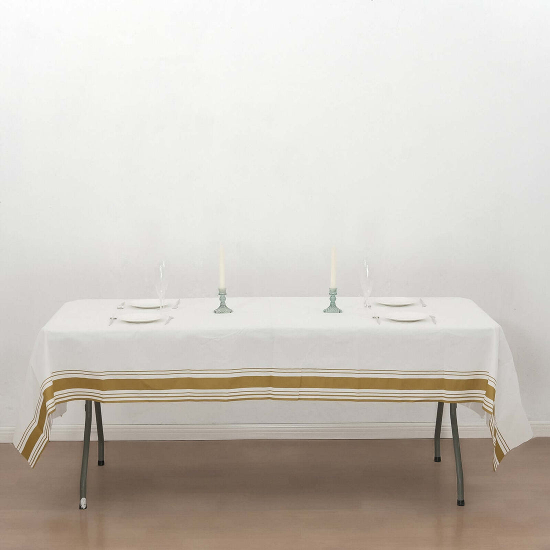 White tablecloth with gold stripes on a dining table set for two.