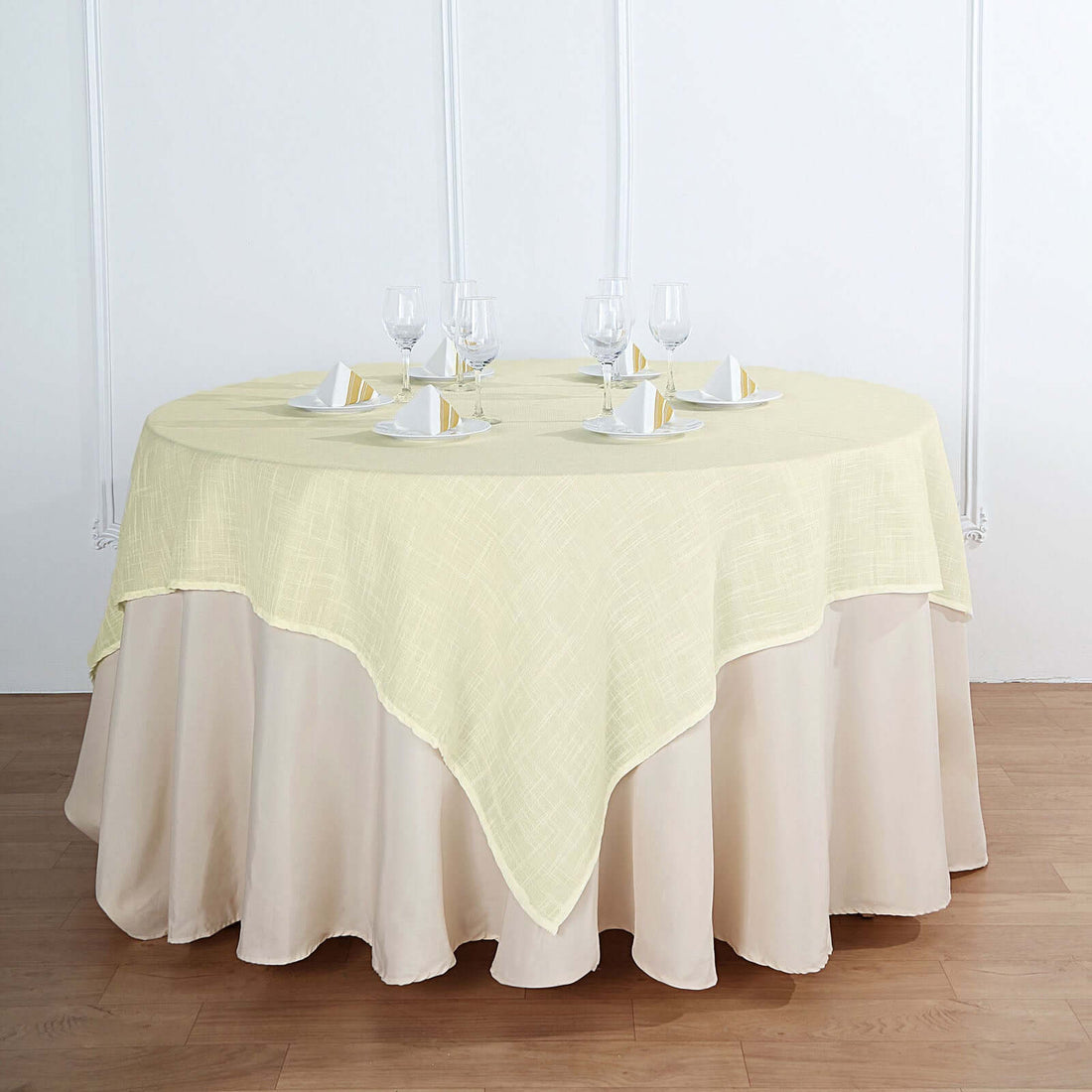 Round yellow tablecloth draped on a table with elegant dinnerware.