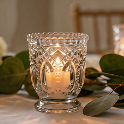 Lit decorative glass candle holder with warm candlelight and eucalyptus leaves