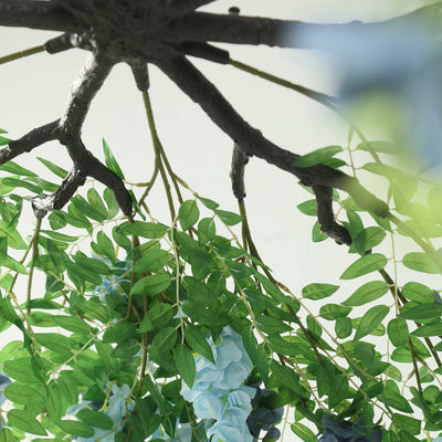 Artificial floral arrangement with blue flowers and green leaves.