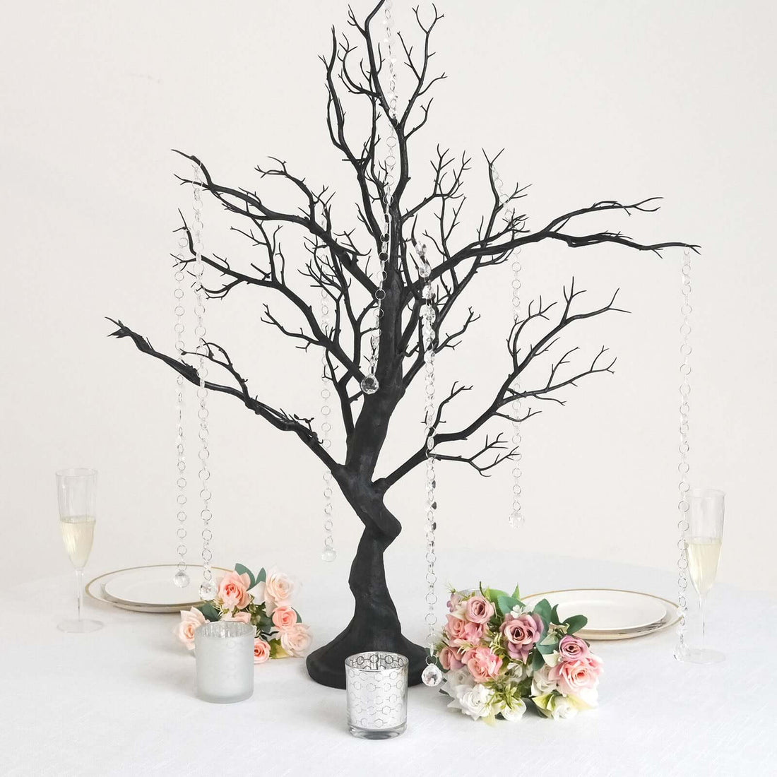 Black decorative tree centerpiece with hanging crystals and floral arrangements.