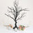 Black decorative tree centerpiece with hanging crystals and floral arrangements.