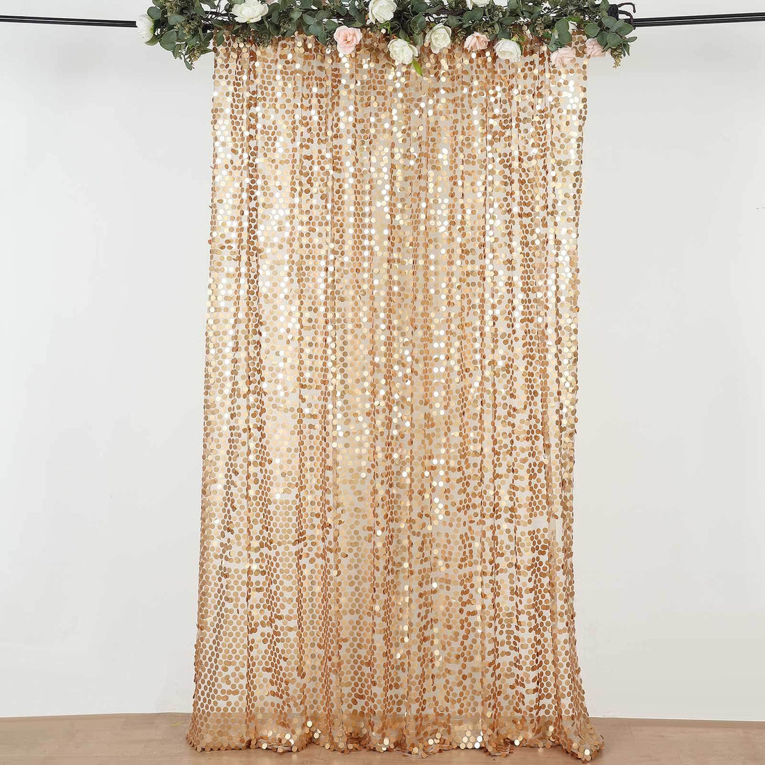 Gold sequin curtain with floral accents hanging from a rod.