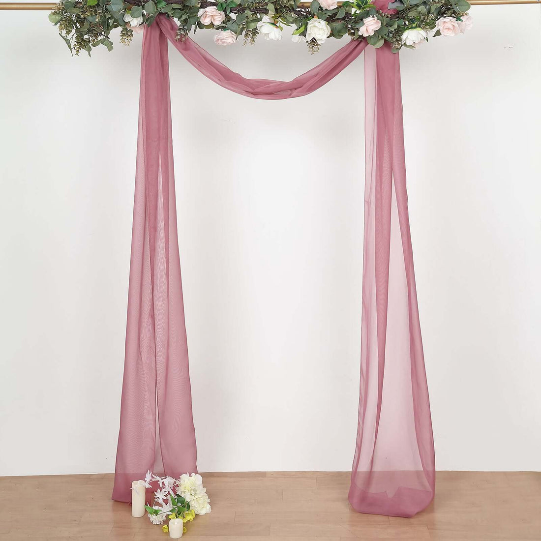 Sheer burgundy drapery with floral accents for event decoration.