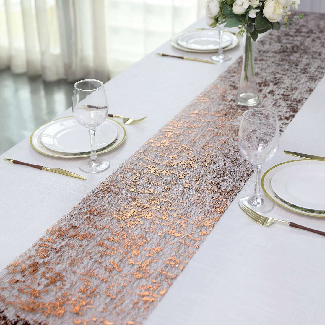 Elegant table runner with copper accents on a white table setting.