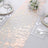 Elegant rose gold table runner on a white table setting with floral decor.