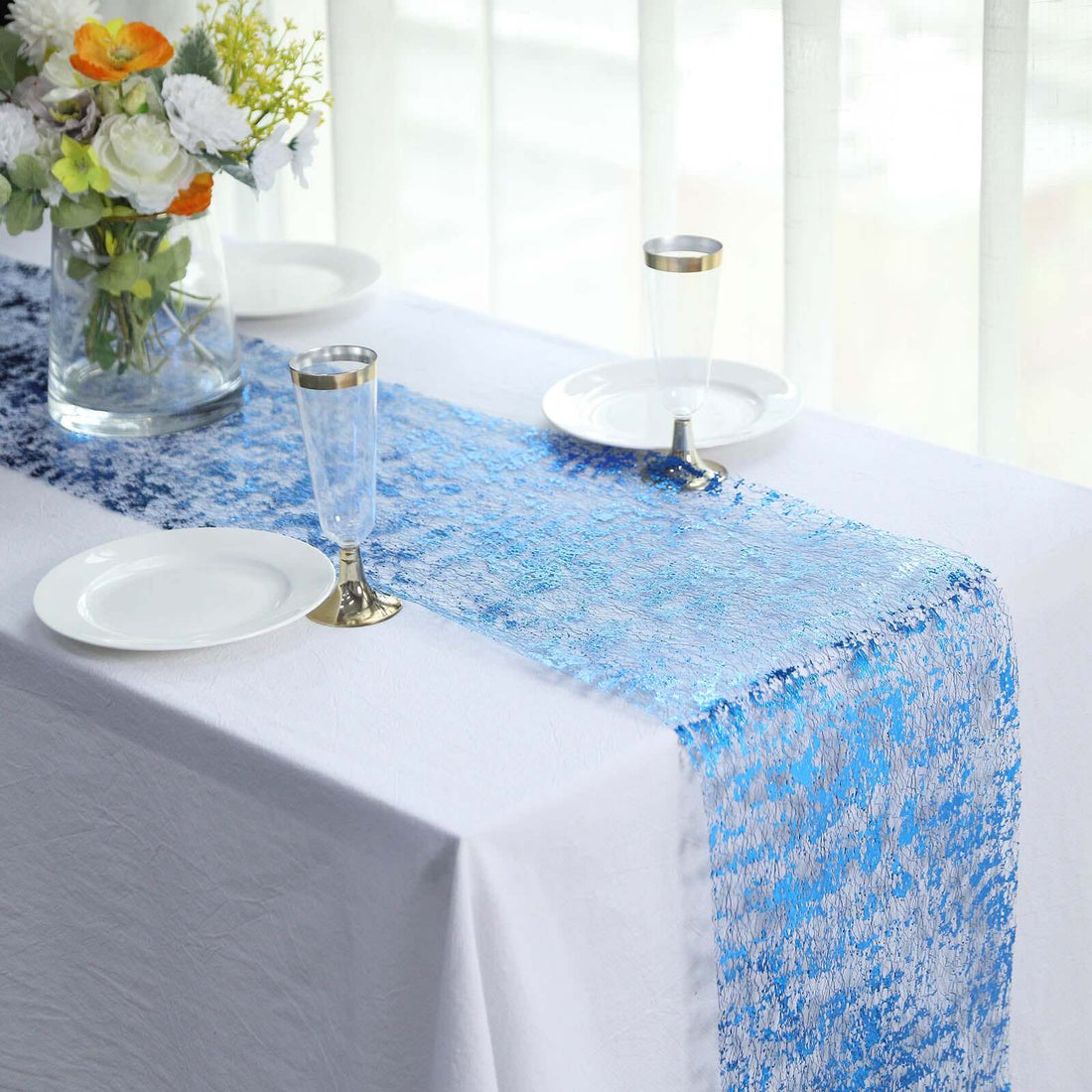 Blue textured table runner on a white table with plates and glasses.