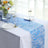 Blue textured table runner on a white table with plates and glasses.