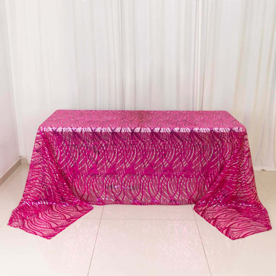 Pink sequined tablecloth on a table against a white backdrop.