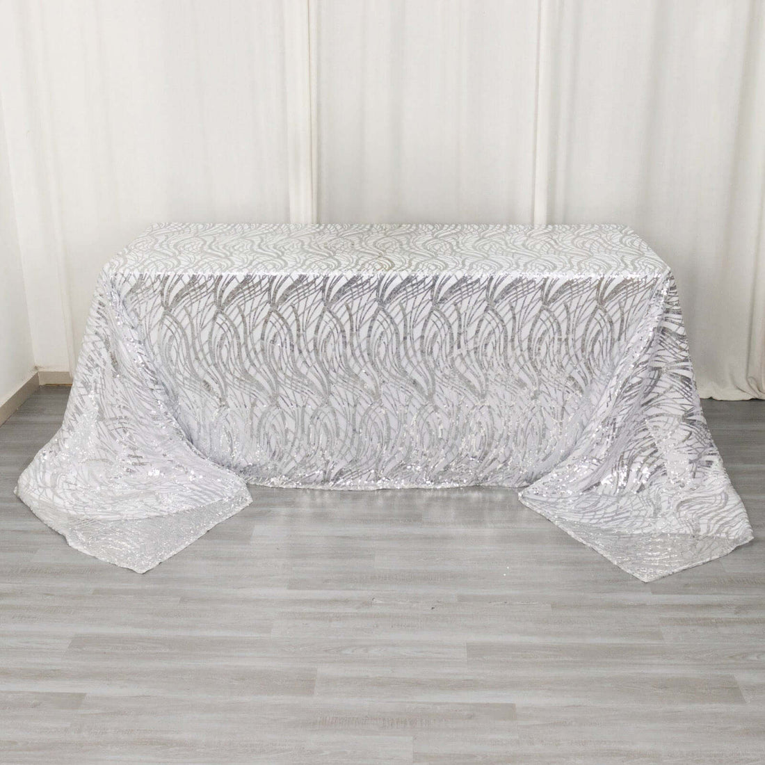 Silver sequin tablecloth with intricate leaf pattern on a table.