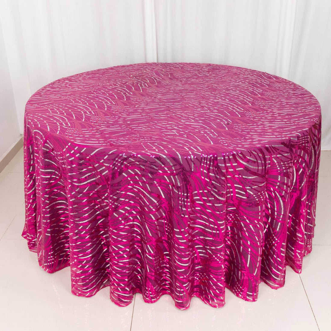 Round pink tablecloth with white swirl pattern on a plain background.