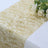 Gold patterned table runner with white roses on a plain background.