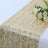 Gold sequin table runner with white roses on a table.